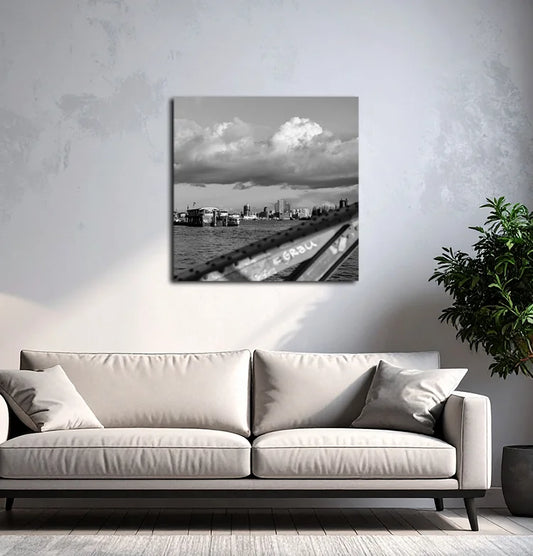 Ein schwarz Weiß Foto der Elbe mit Elbphilharmonie, Hanseatic Trade Center, Fähren und einem Brückenbogen, an einer hellen wand mit grauem Sofa