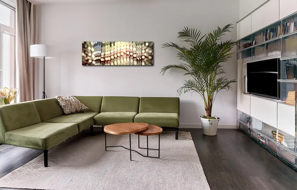 Das abstrakte Werk im Panoramaformat hängt an einer hellen Wand in einem modernen Wohnraum mit hellgrünem Sofa