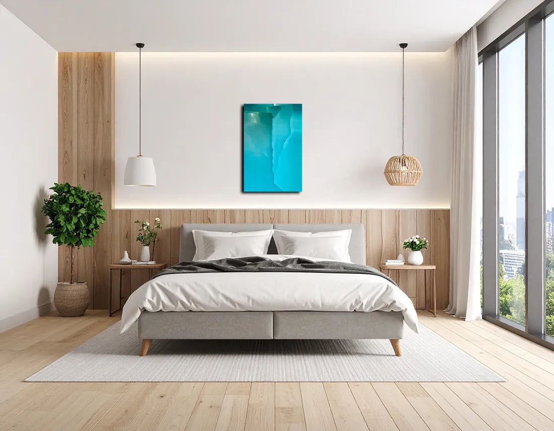 Abstraktes Foto das blaue und türkise Strukturen zeigt die durch Stoff fotografiert wurden, an heller Wand in einem Schlafzimmer hängend.