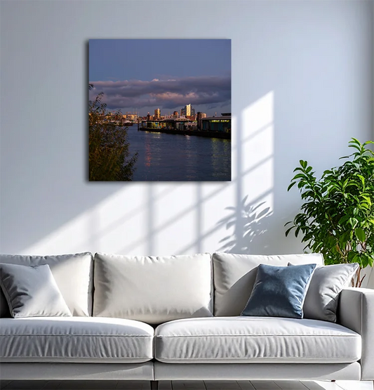 Farbfotografie des Hafens, das Abendlicht spiegelt sich in der Fassade der Elbphilharmonie, leichte Wolken am Himmel, an heller Wand hängend mit weißem Sofa