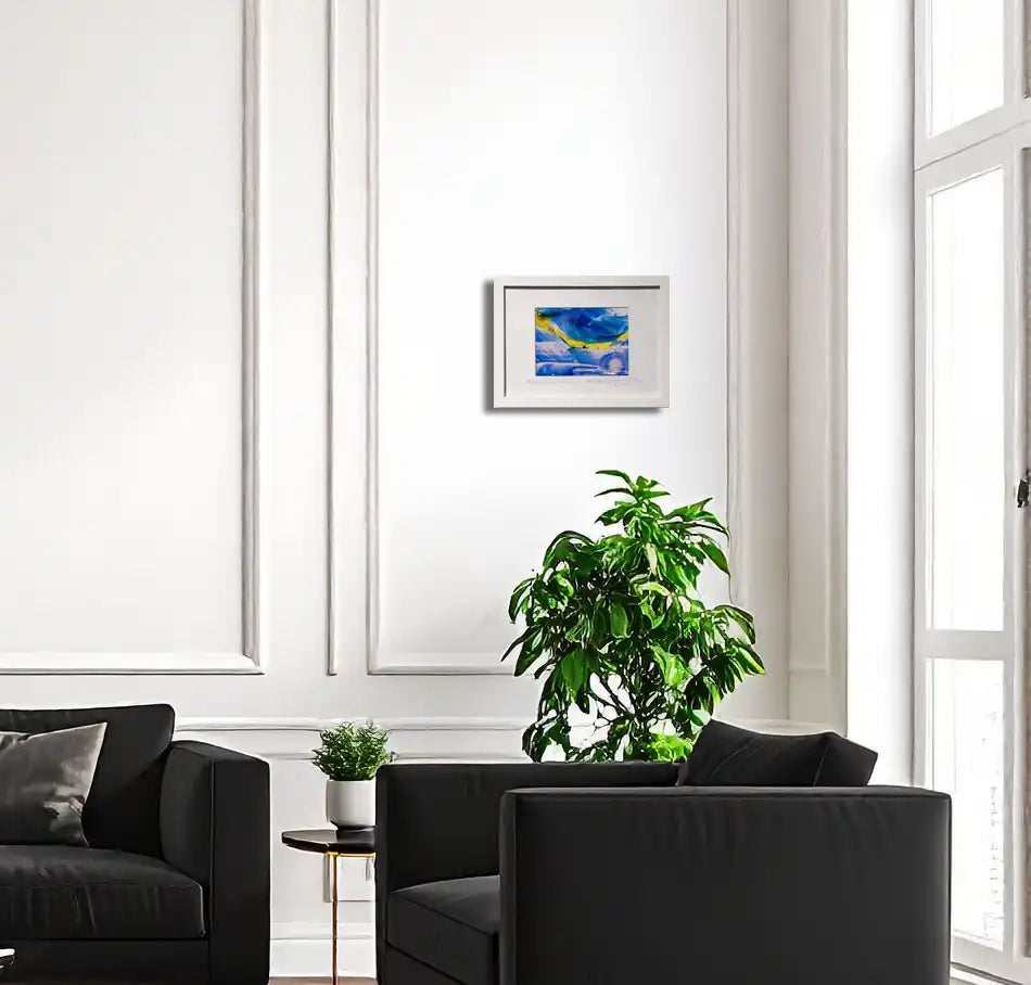 abstraktes Gemälde in Gelb, Blau, weiß in Passepartout mit weißem Rahmen, an heller Wand in Wohnraum hängend mit schwarzem Sessel.