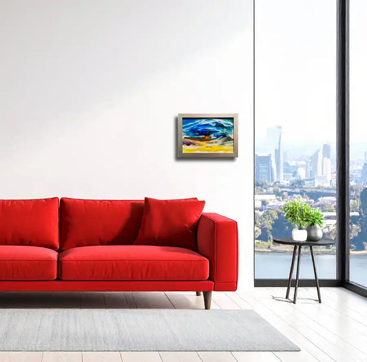 abstraktes Gemälde in Gelb, Blau, orange goldenem Rahmen, horizontale Streifen an heller Wand in Wohnraum mit rotem Sofa hängend.