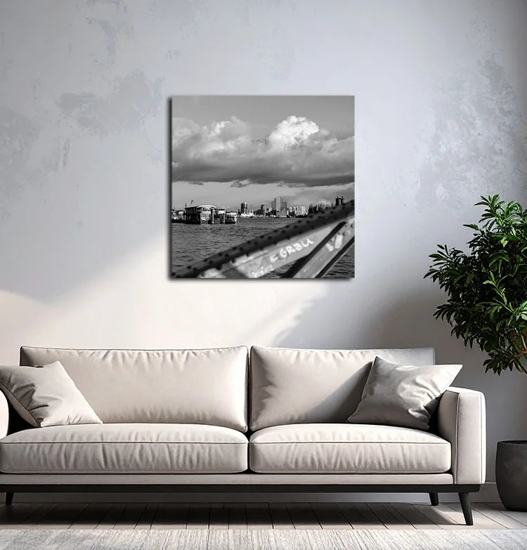 Ein schwarz Weiß Foto der Elbe mit Elbphilharmonie, Hanseatic Trade Center, Fähren und einem Brückenbogen, an einer hellen wand mit grauem Sofa