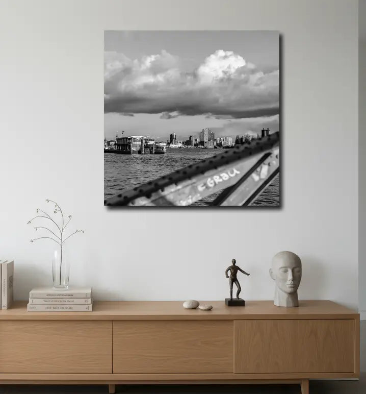 Schwarz weiß Foto über die Elbe, im Hintergrund die Elbphilharmonie und HTC, im Vordergrund ein unscharfer Brückenpfeiler, an heller Wand hängend