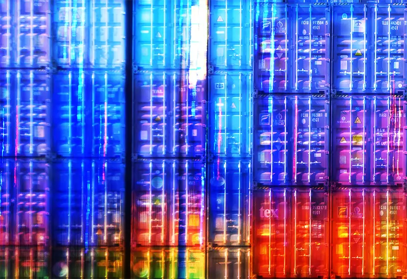 Gestapelte Container in verschiedenen Farben mit hellen Farbfeldern, Detailansicht einiger blauer und roter Container