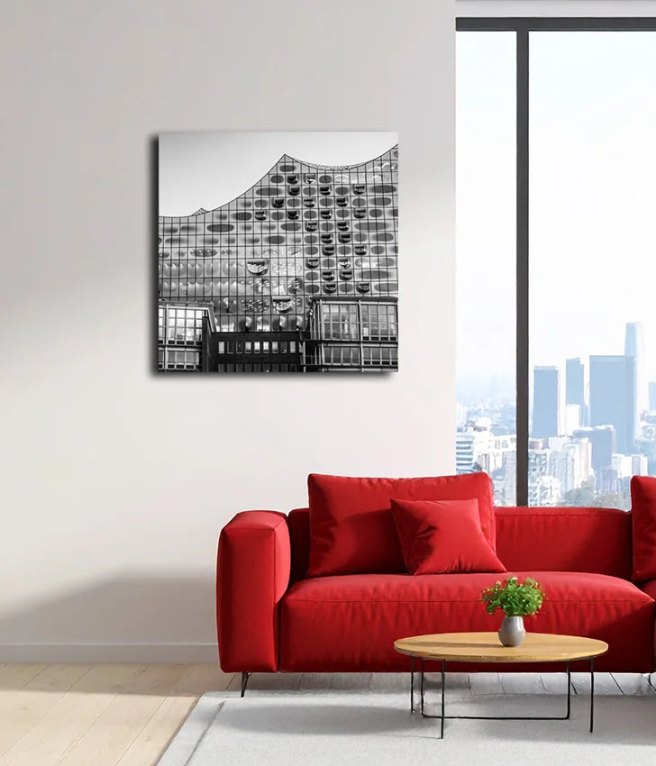 Schwarz-weiß Foto der Elbphilharmonie, Detaiausschnnitt, an heller Wand hängend mit roten Sofa