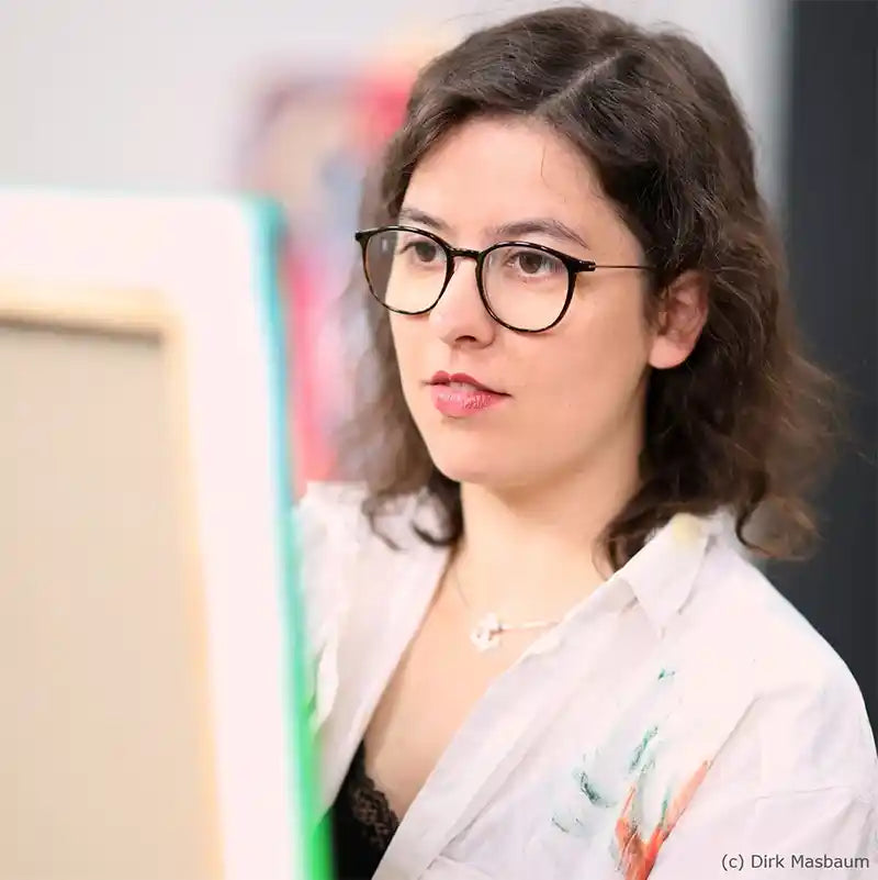 Portrait Vanessa Nafzger, malt auf einer Leinwand, konzentrierter Blick, Malerkittel