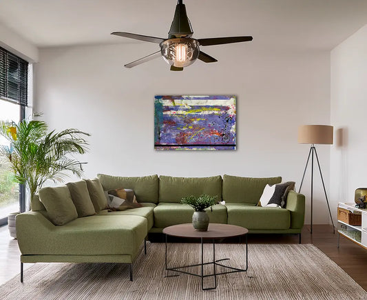 ein abstraktes Gemälde im querfomat, gelbe und violette Strukturen, an einer hellen Wand hängend im modernen Wohnraum mit grünem Sofa und Lampe