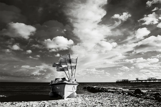 Kellenhusen – Fotokunst von Birte Zabel, Schwarz-Weiß-Fotografie, Fischerboot am Ostseestrand vor dramatischem Wolkenhimmel | Kunst-Direkt.de

