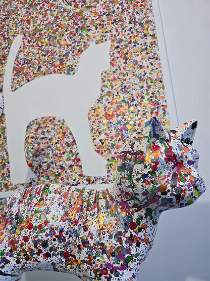 Eine bunte Katze steht vor einer bunten Leinwand mit den Umrissen  der Katze, Details des Katzenkopfes.