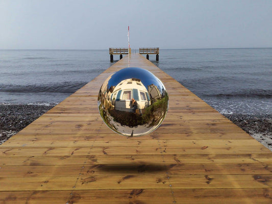 Eine Kugel schwebt über einem Steg der in die Ostsee führt-Surreales Werk