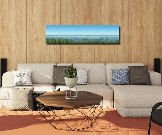 Panoramafoto des Watts vor Sylt, eine Möve ist zu sehen, weiter Horizont mit Nordsee, an Holzwand hängend mit hellem Sofa